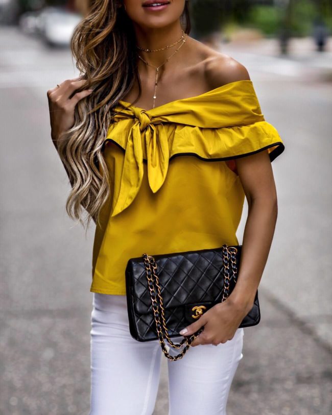 fashion blogger mia mia mine wearing a gold top from revolve and a chanel bag